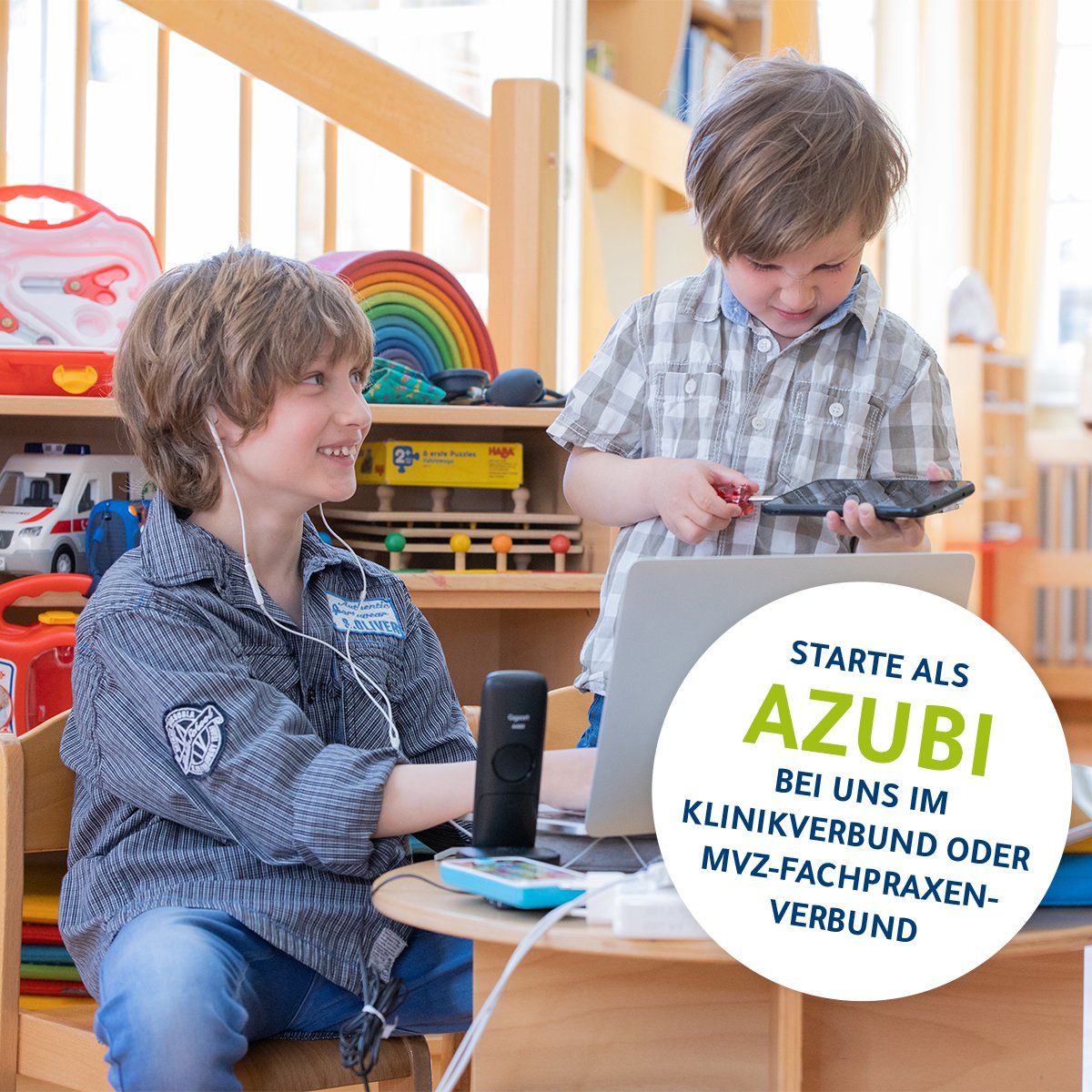 Zwei Kinder spielen als Erwachsene verkleidet mit einem PC. Im Hintergrund stehen medizinische Taschen und Koffer.